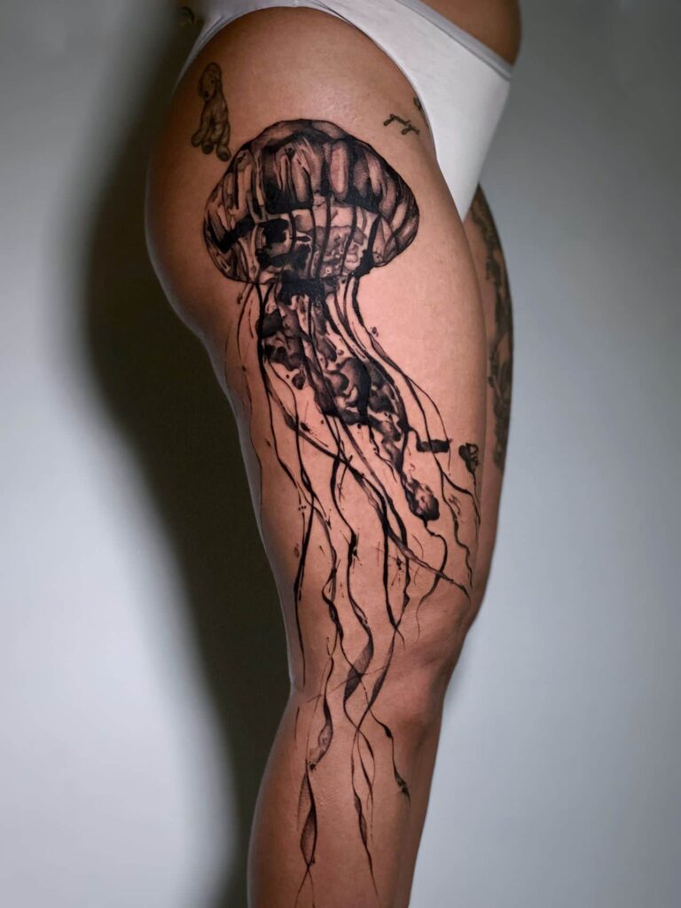 A woman showing off her thigh tattoos, highlighting intricate designs and vibrant colors.