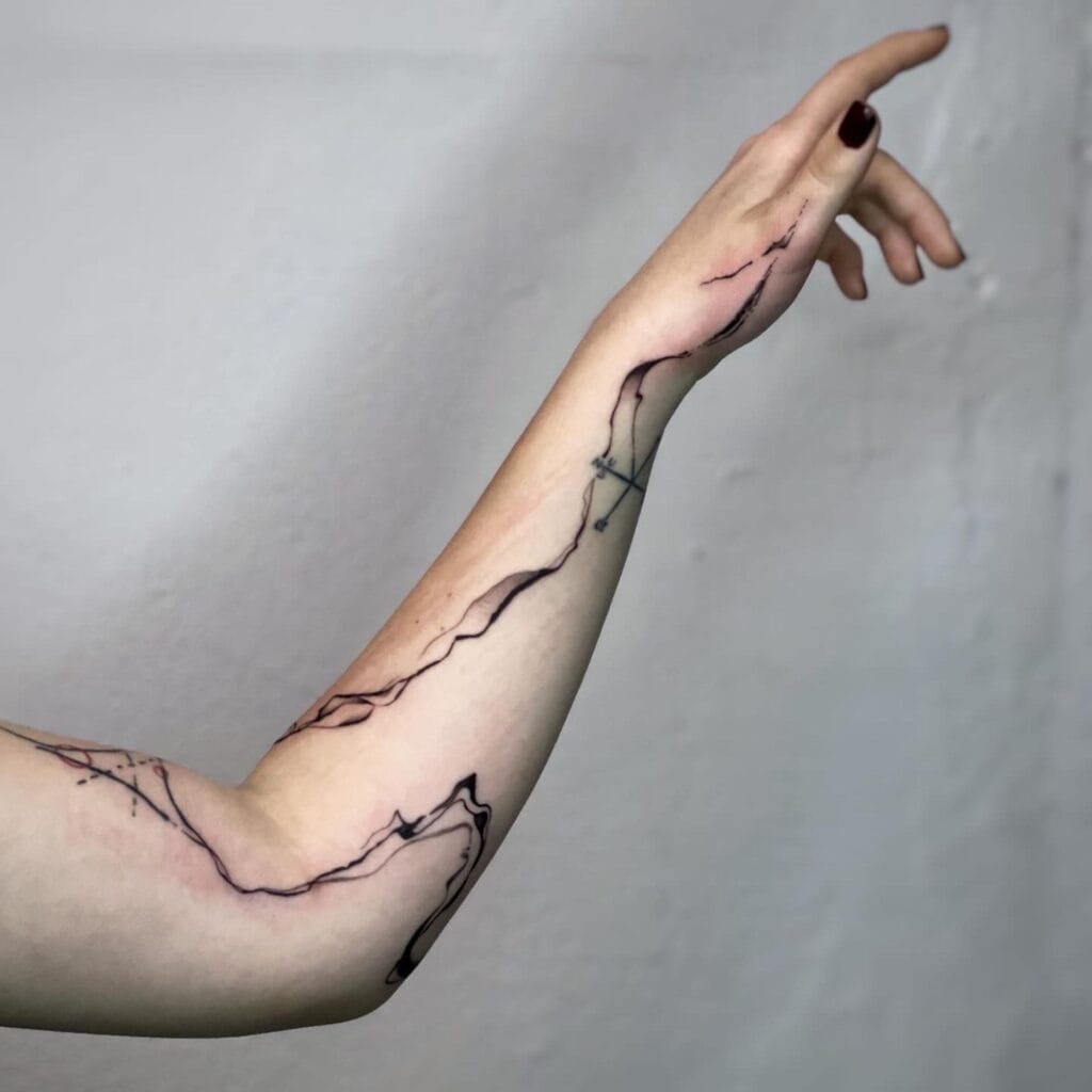 A woman showing off her arm tattoo, highlighting intricate designs and vibrant colors.