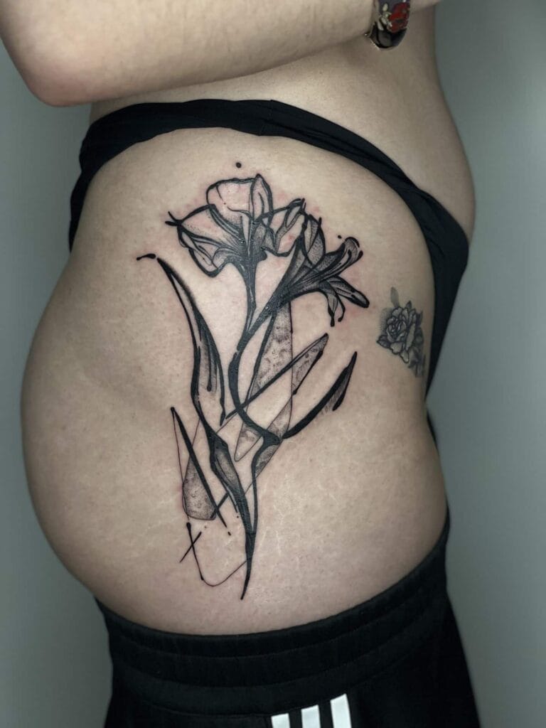 A close-up of a woman's stomach featuring a vibrant flower tattoo, showcasing intricate details and colors.