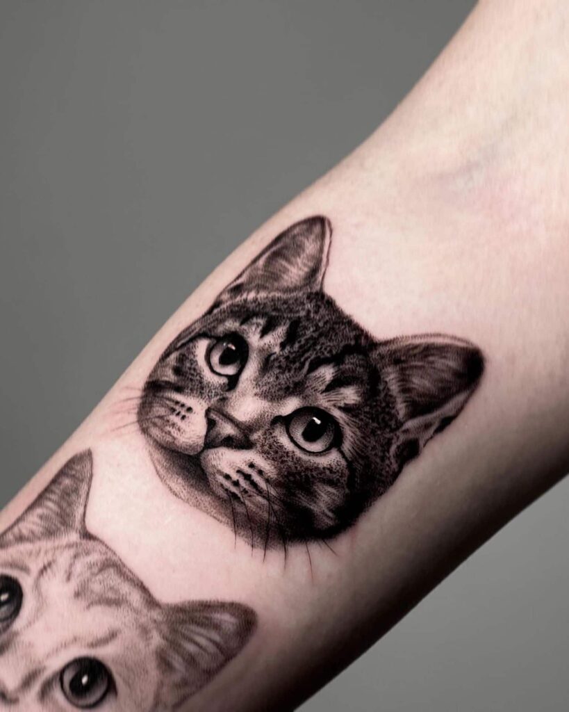Tattoo of two playful cats inked on a person's arm, showcasing their love for feline companions.