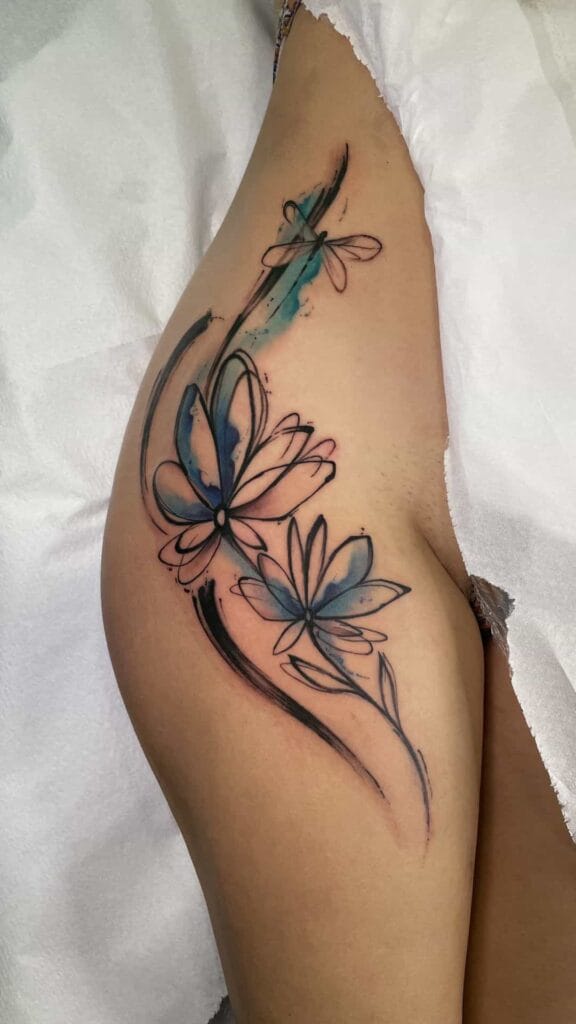 A close-up of a woman's thigh featuring a detailed flower tattoo, showcasing intricate designs and vibrant colors.