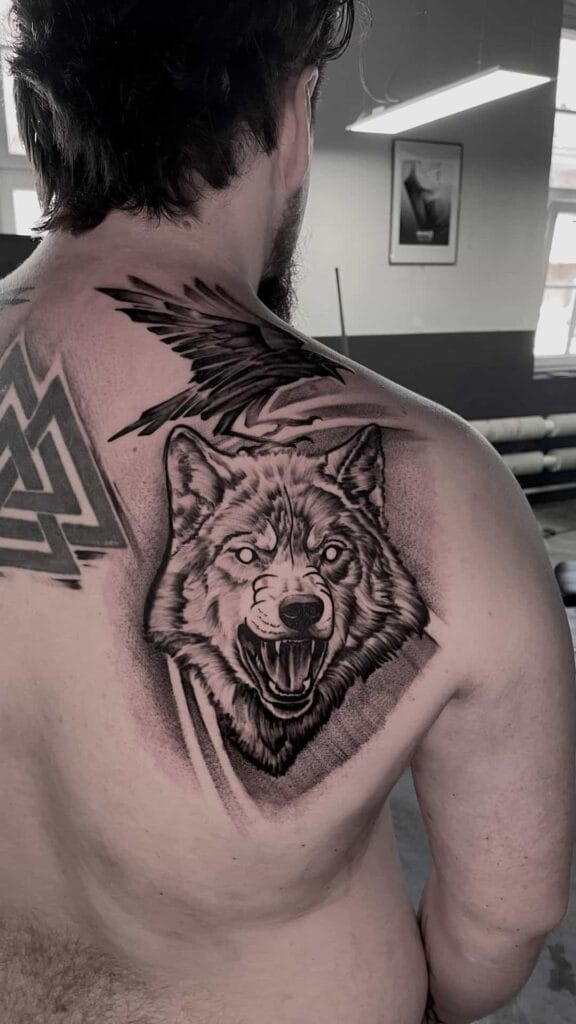 A man showing off a detailed wolf tattoo on his back, highlighting the intricate design and bold colors.