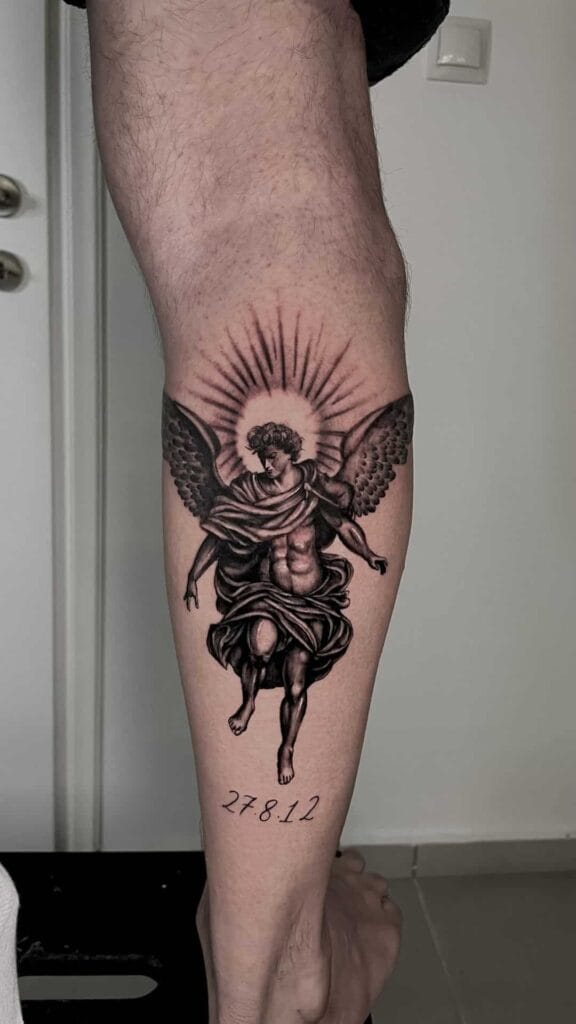 A man's leg featuring a detailed tattoo of an angel, showcasing intricate wings and a serene expression.