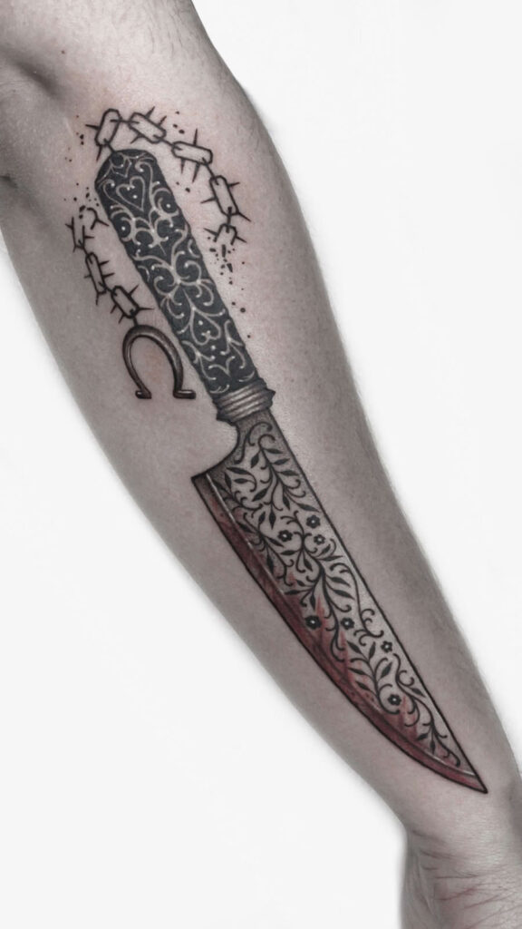 Ornamental blackwork tattoo of a decorative knife with intricate patterns, barbed wire, and a horseshoe, designed by Achlys at Uncle Chronis.